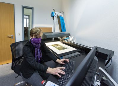 Frau mit Schal vor dem Gesicht sitzt vor dem Hochleistungsscanner in der Grafischen Sammlung des Historischen Museums Frankfurt