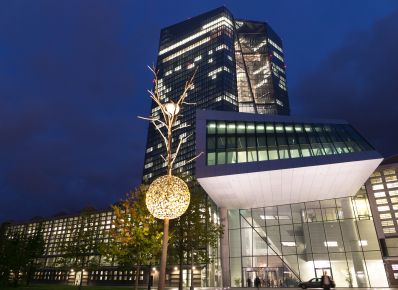 Eingang zur Europäischen Zentralbank mit kleinem Baum mit Lichtkugel im Vordergrund, dahinter verglastes Hochhaus 