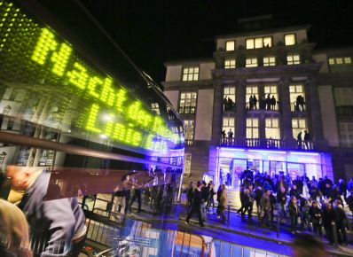 Windschutzscheibe des Nacht der Museen-Bus vor dem Eingang des Filmmuseums mit Menschen